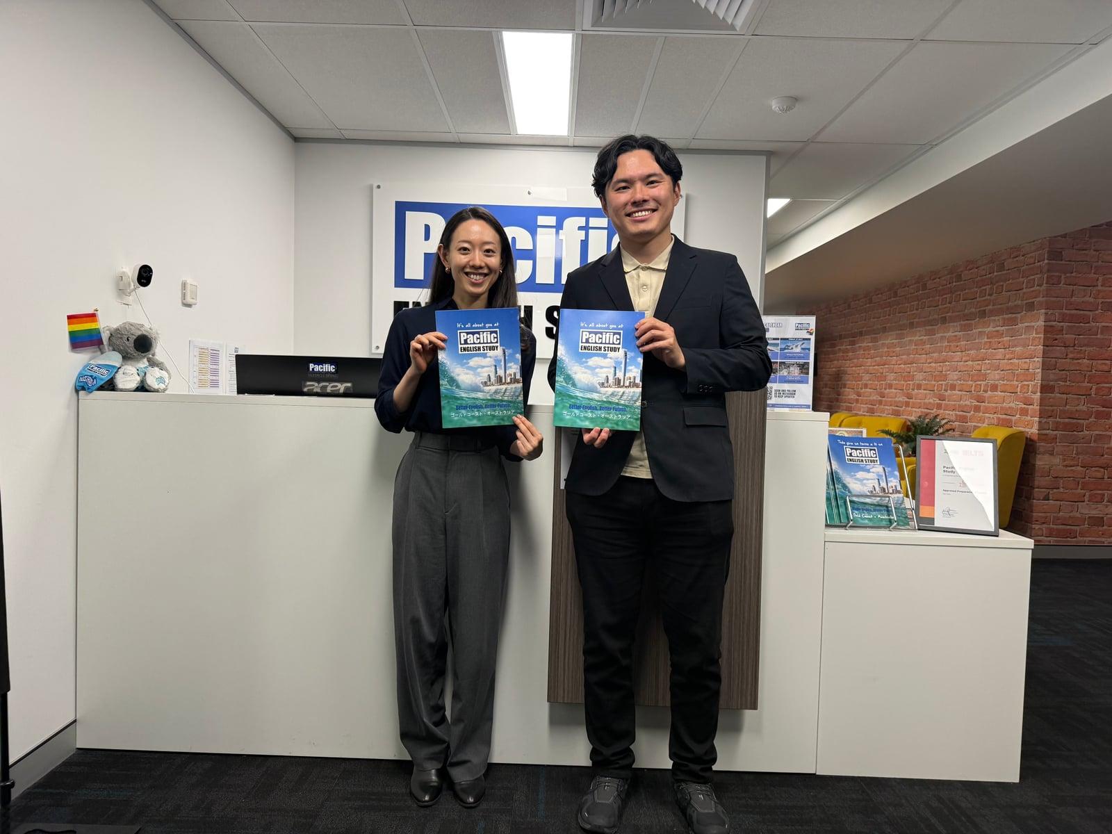 Pacific English Study の受付で、パンフレットを持った学校担当者と成功する留学の代表が撮影した写真