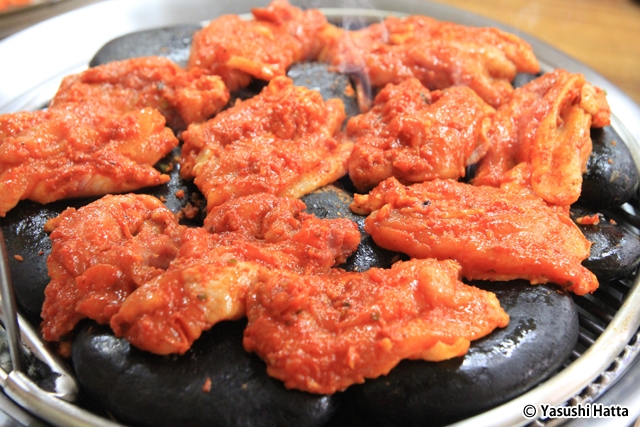 石の表面で鶏肉を焼く。焼けムラができないよう配置に注意が必要