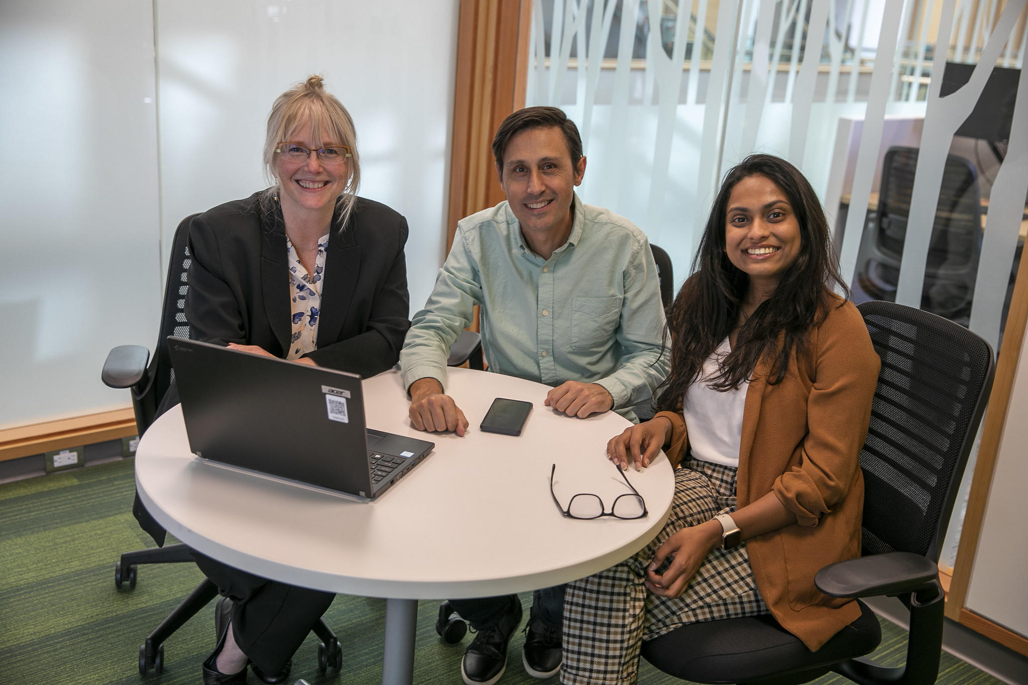Three employees engaging and discussion in a meeting room in CHW building at Interurban campus